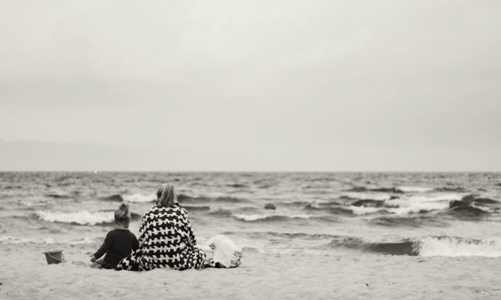 mamma con figlia sedute sulla spiaggia