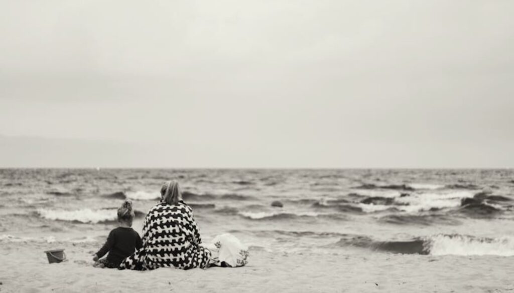 mamma con figlia sedute sulla spiaggia