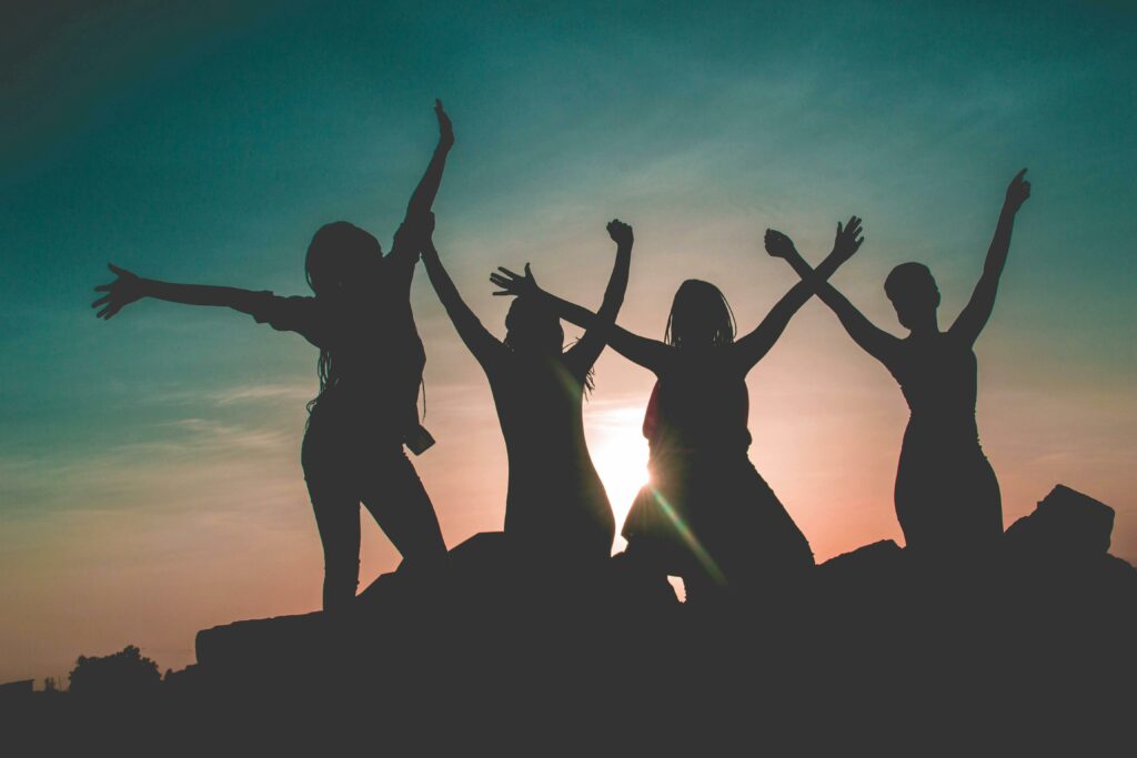 Natura ribelle - quattro ragazze sono riprese al tramonto. Si vedono solo le loro sagome. Hanno le braccia alzate verso il cielo in segno di felicità, di lotta.